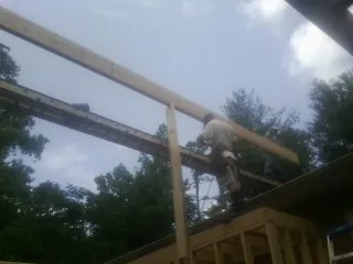 Carpenter setting a ridge beam over a new addition frame — Ice Dam Removal by Roofing Brothers in Oreland