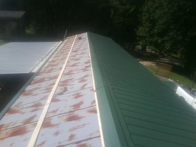 Old rusted panels beside newly installed green metal roofing — Wind Damage Roof Repair by Roofing Brothers in Oreland