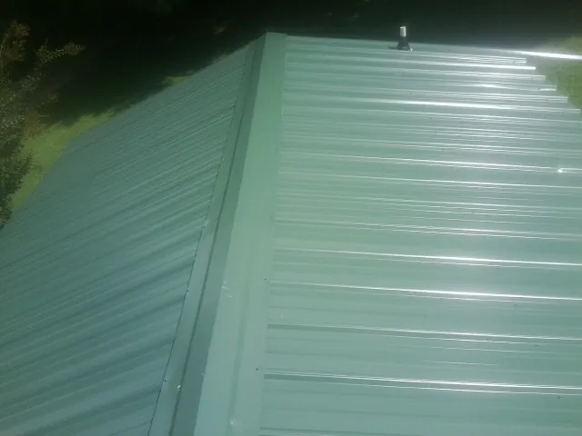 New green metal panels meeting at the ridge of a roof — Flat Roof Repair work by our crew in Oreland