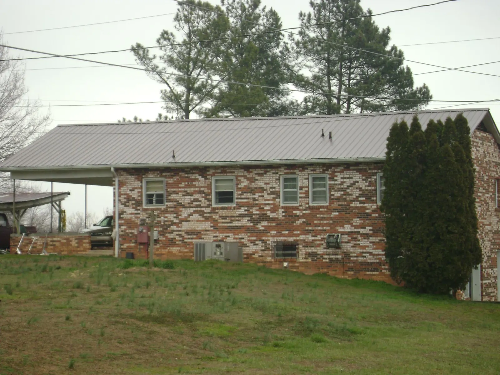 Gray metal roof on a brick split level home with a carport in Oreland
