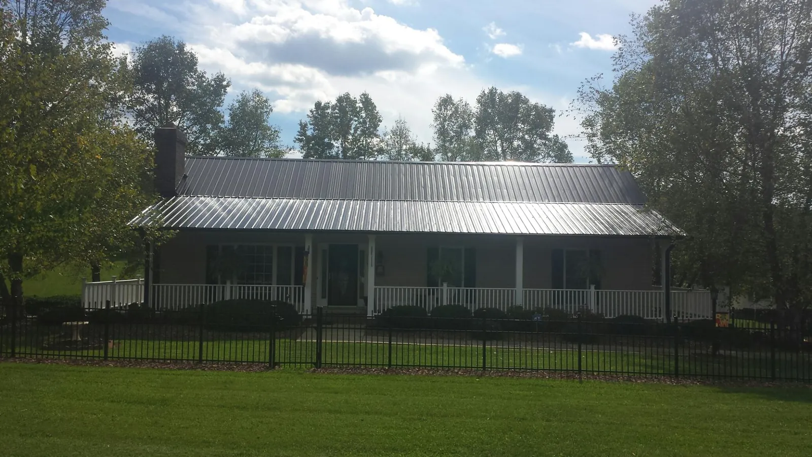 Gray metal roof on a brick ranch with a full width front porch — Gutter Guard Installation work by our crew in Oreland
