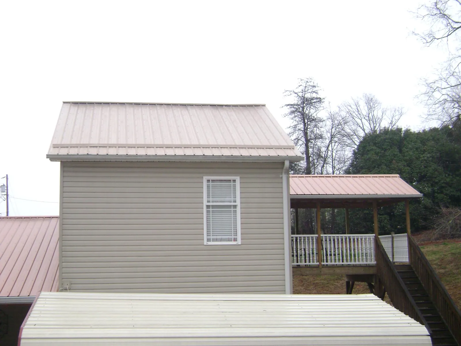 Tan metal roofs on a two story addition and attached porch, from a Roof Replacement job in Oreland