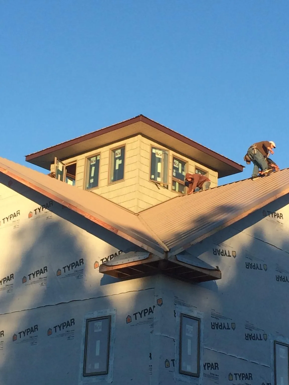 Roofers working around a rooftop cupola on a new metal roof at sunset — Roof Waterproofing in Oreland by Roofing Brothers